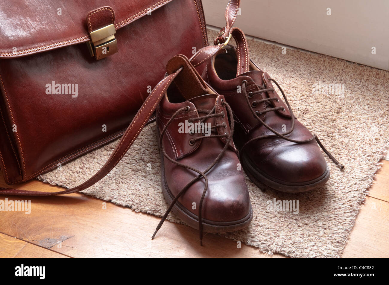 Braune Lederschuhe und Aktenkoffer auf eine Fußmatte durch eine Tür. UK Stockfoto