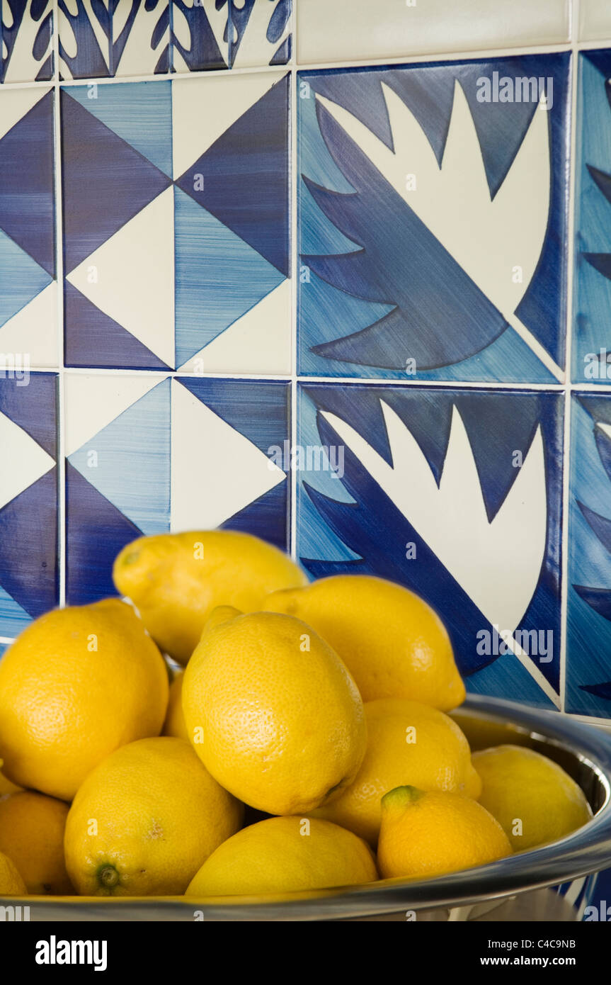 Nahaufnahme einer Schale der Zitronen vor zeitgenössischen blauen und weißen Fliesen Stockfoto