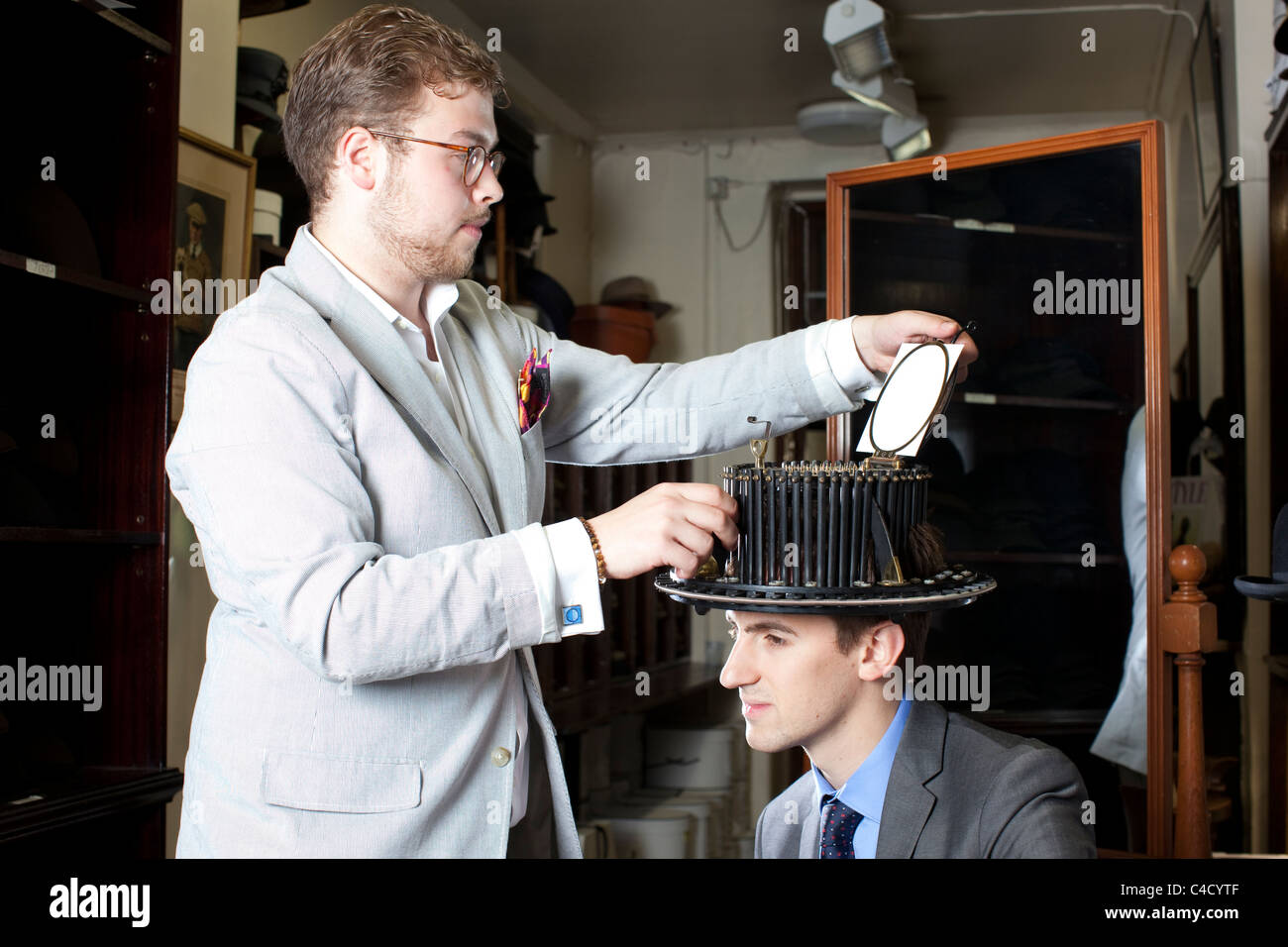 Mann mit Conformateur Gerät auf Kopf während Kopf gemessen für Top Seidenhut auf Schloss & Co hatters,London.Photo:Jeff Gilbert Stockfoto
