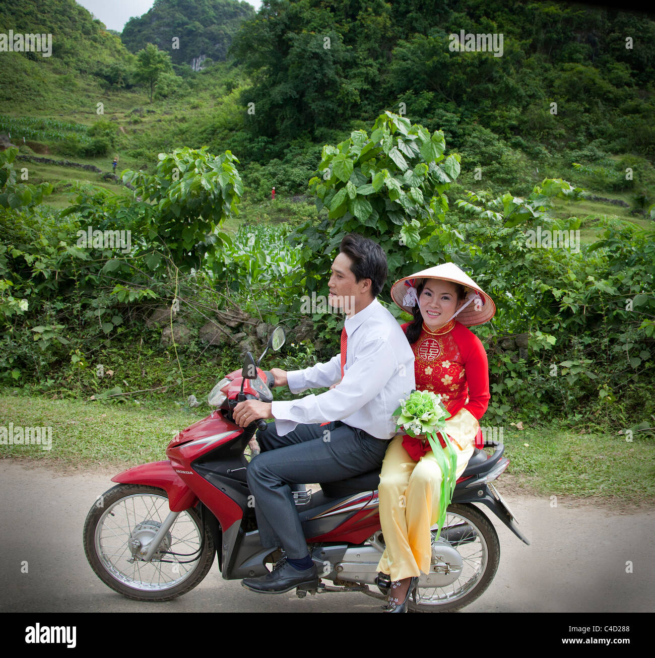 Vietnamesische Brautpaar auf einem Motorrad auf dem Weg zu einer Zeremonie Stockfoto