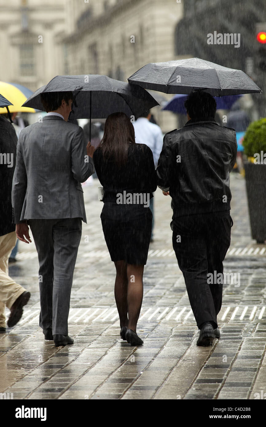 London City Arbeitnehmer im Regen mit Sonnenschirmen in Queen Street, London, UK. Stockfoto