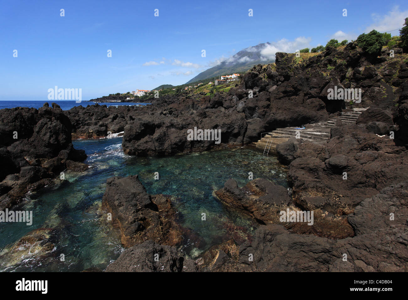 Einen Panoramablick über einen natürlichen Meerwasserpool im São João, Pico, Azoren, mit Blick auf Pico Inselberg Stockfoto