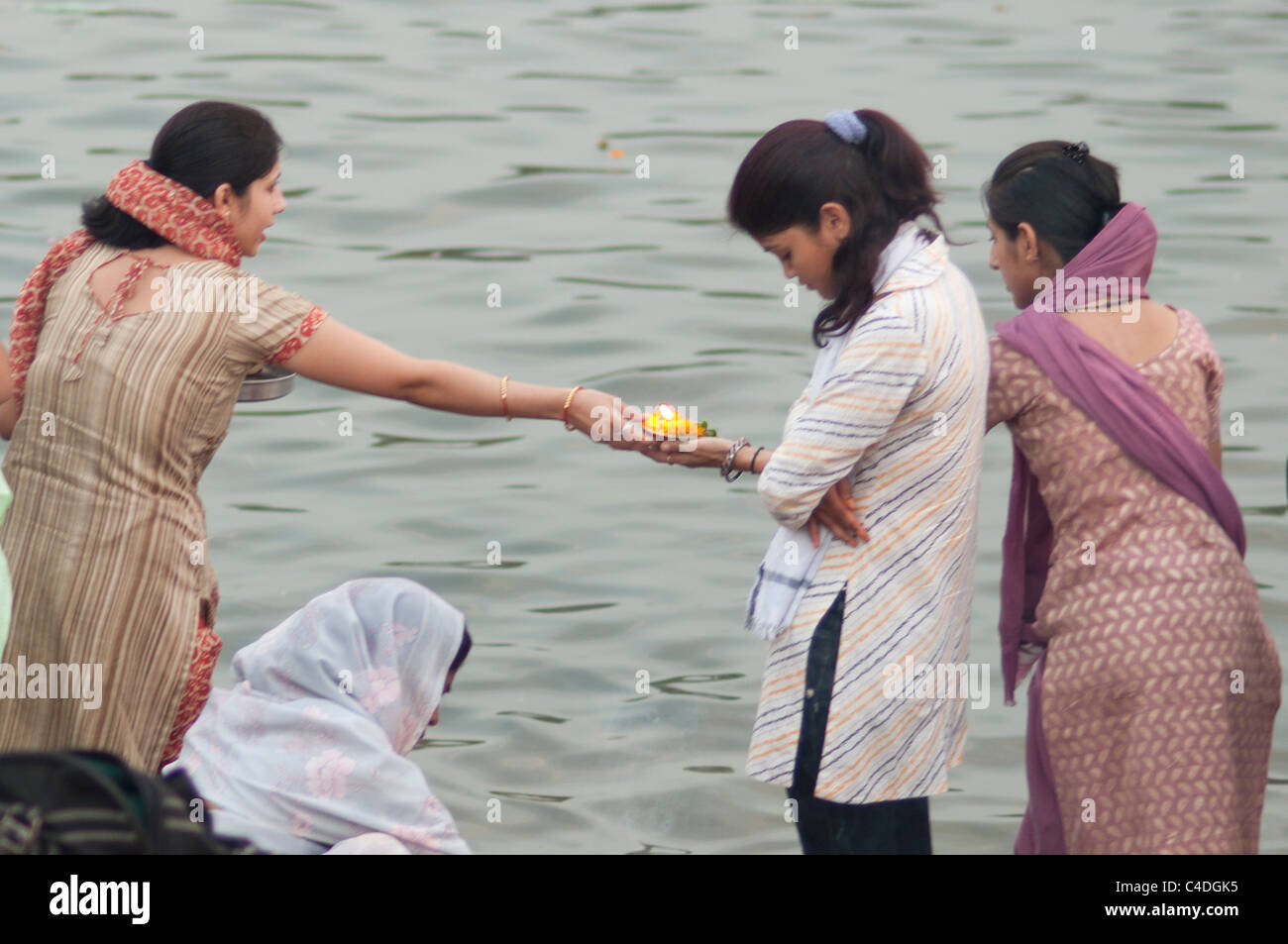 Eine Dame, die eine religiöse Lampe an der andere Dame am Ufer des Flusses Narmada übergeben. Stockfoto