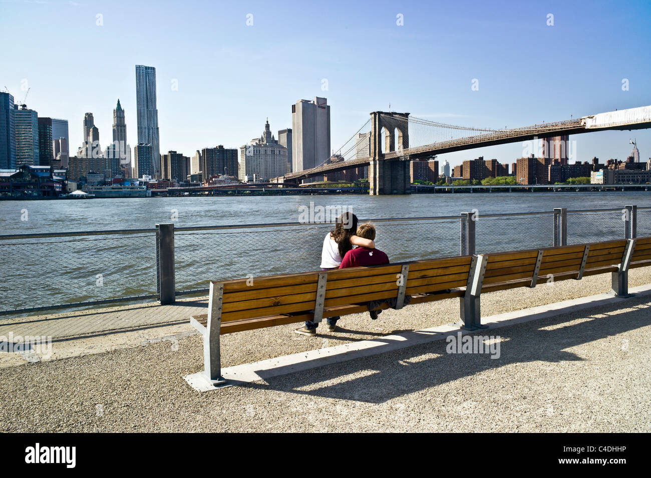 einsame umwerben paar sitzen auf Bank der Brooklyn Bridge Park Esplanade mit Blick auf East River & unteren Skyline von Manhattan Stockfoto