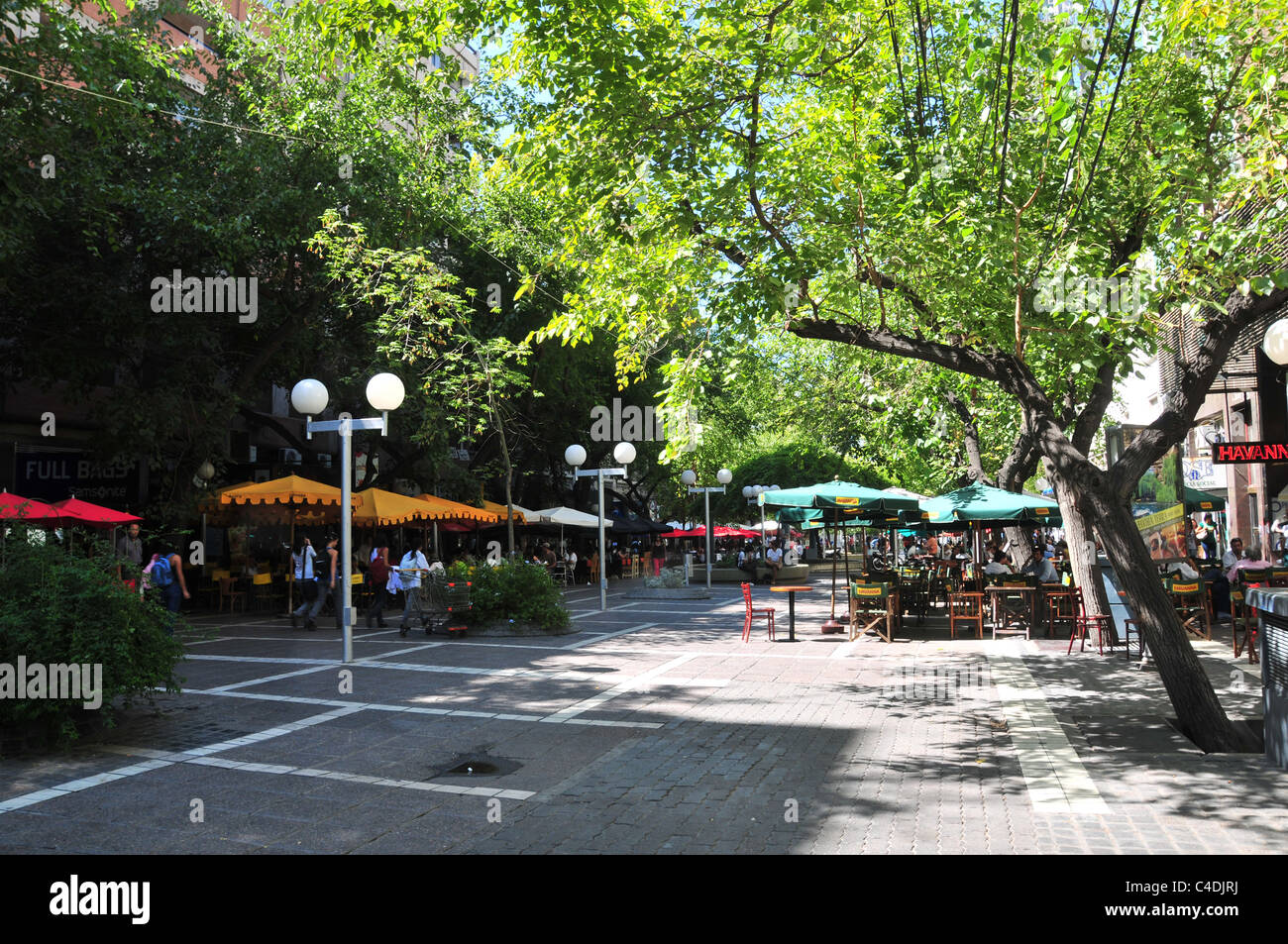 Sonnige Aussicht auf Straßenbäume und Gäste sitzen unter Sonnenschirmen Schattierungen entlang der Fußgängerzone Paseo Sarmiento, Mendoza, Chile Stockfoto