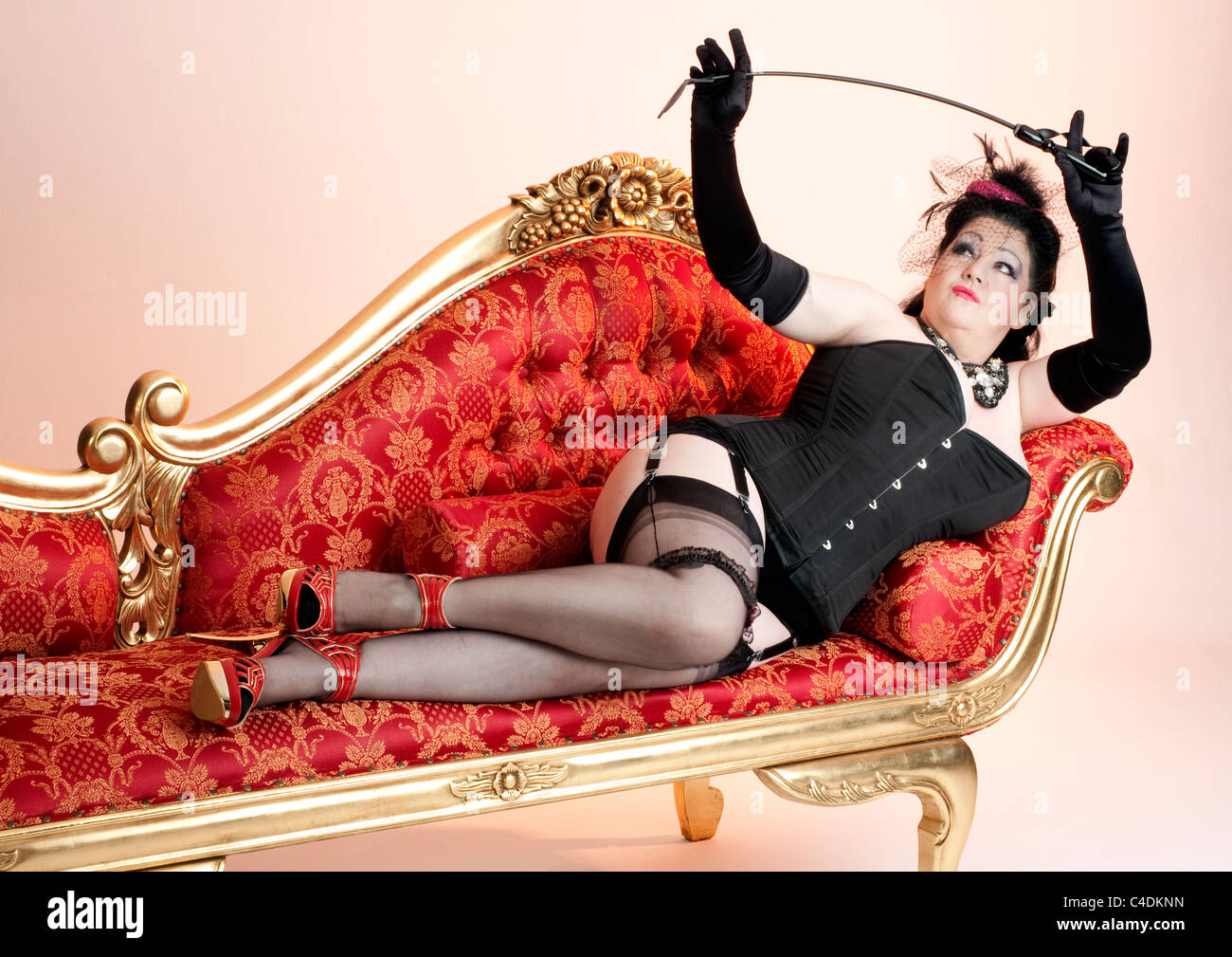 Entspannen Sie sich auf einer Chaiselongue beugen ihrer Reitgerte oder  Peitsche tragen Korsett und Seidenstrümpfe sexy Domina Stockfotografie -  Alamy