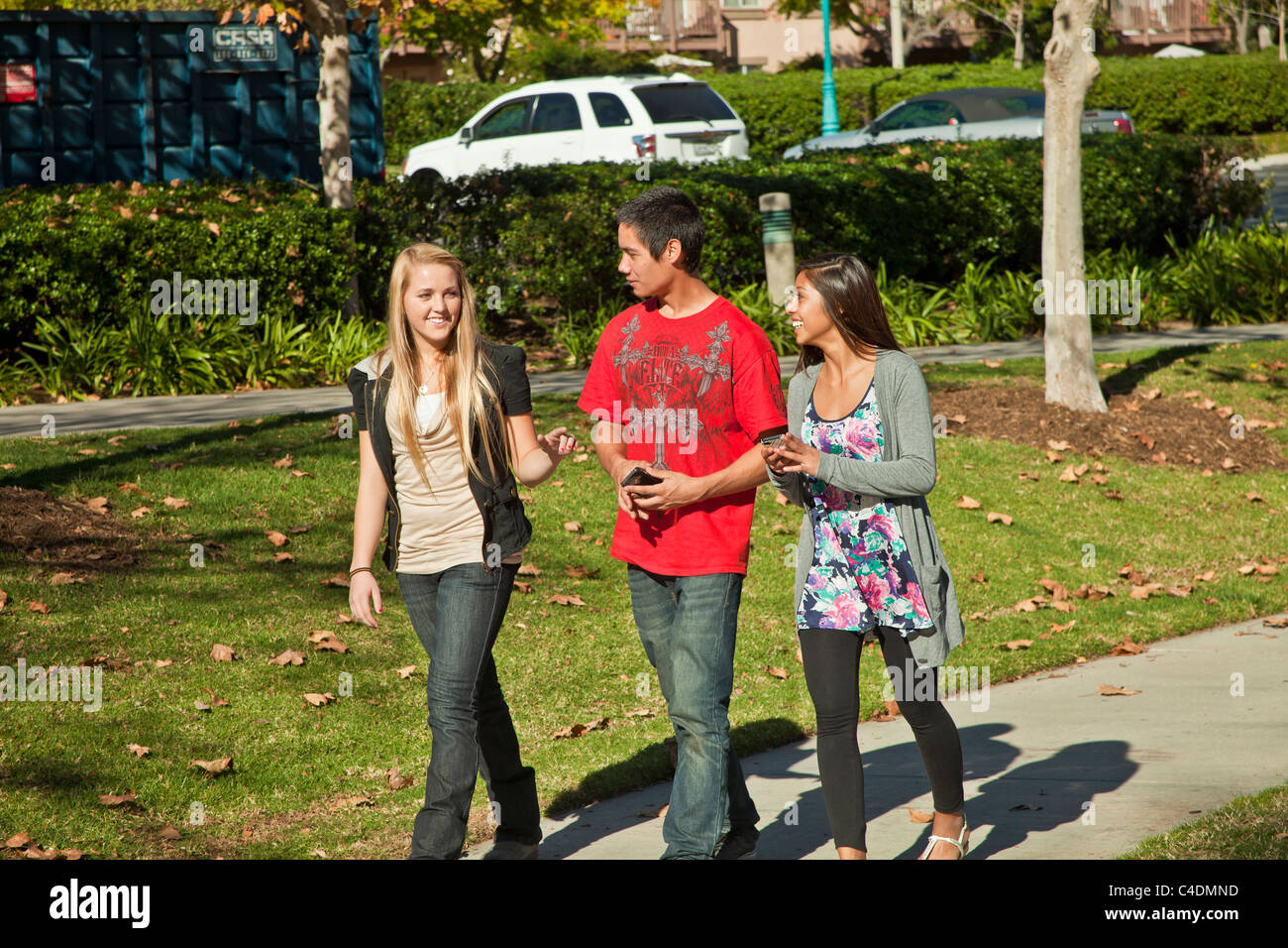 Kalifornien Multi ethnischen Rasse ethnisch Jugendliche zu Fuß reden Indianer, Hispanic Jugendliche mit iPhone Handys Handy Stockfoto