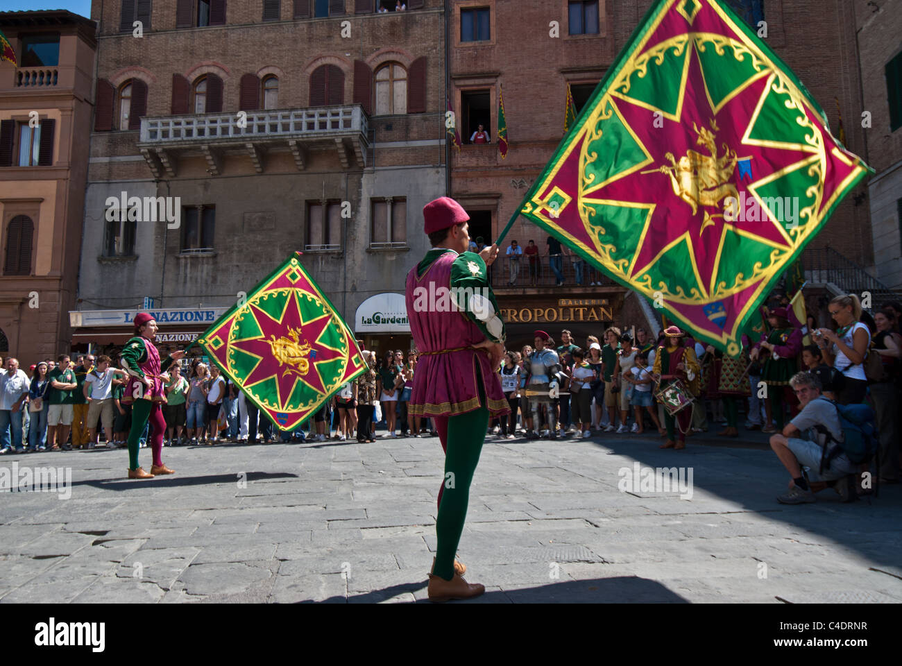 Siena am Tag der berühmte Palio-Pferderennen mit Flaggen und Fahnen schmücken die Straßen und der Festzug vor dem Rennen. Stockfoto