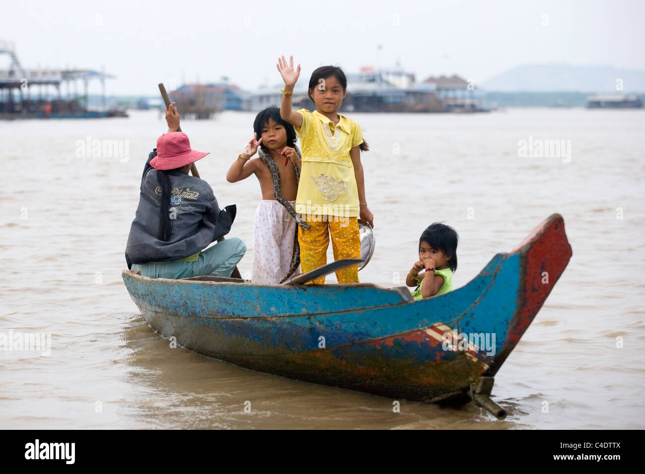 Eine kambodschanische Boot vierköpfige Familie mit einer Schlange, die Kamera auf dem Tonle Sap See in der Nähe von Siem Reap in Kambodscha winken Stockfoto