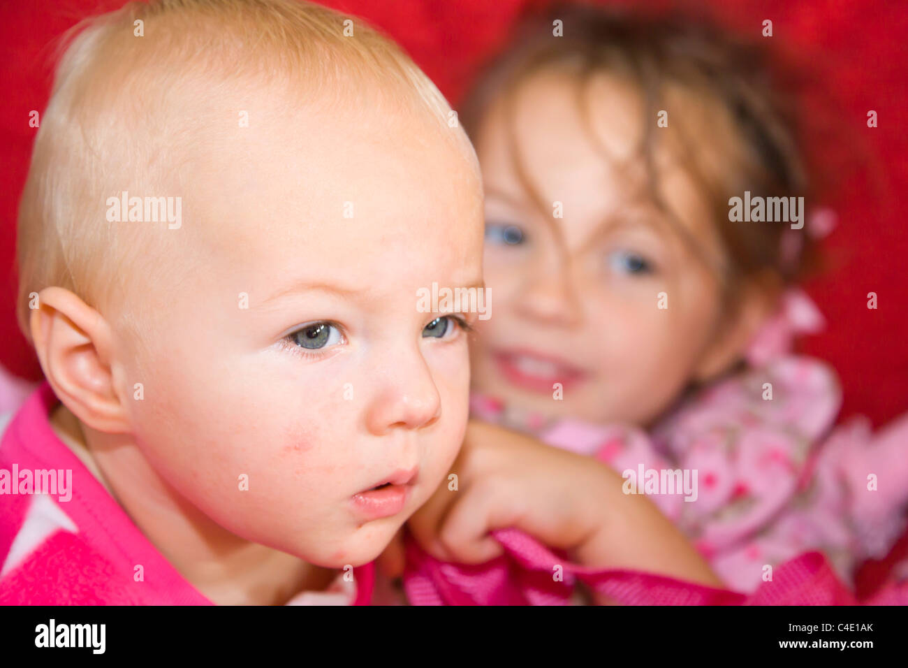 10 Monate und 4 Jahre alten Schwestern in rosa Schlafanzug Stockfoto