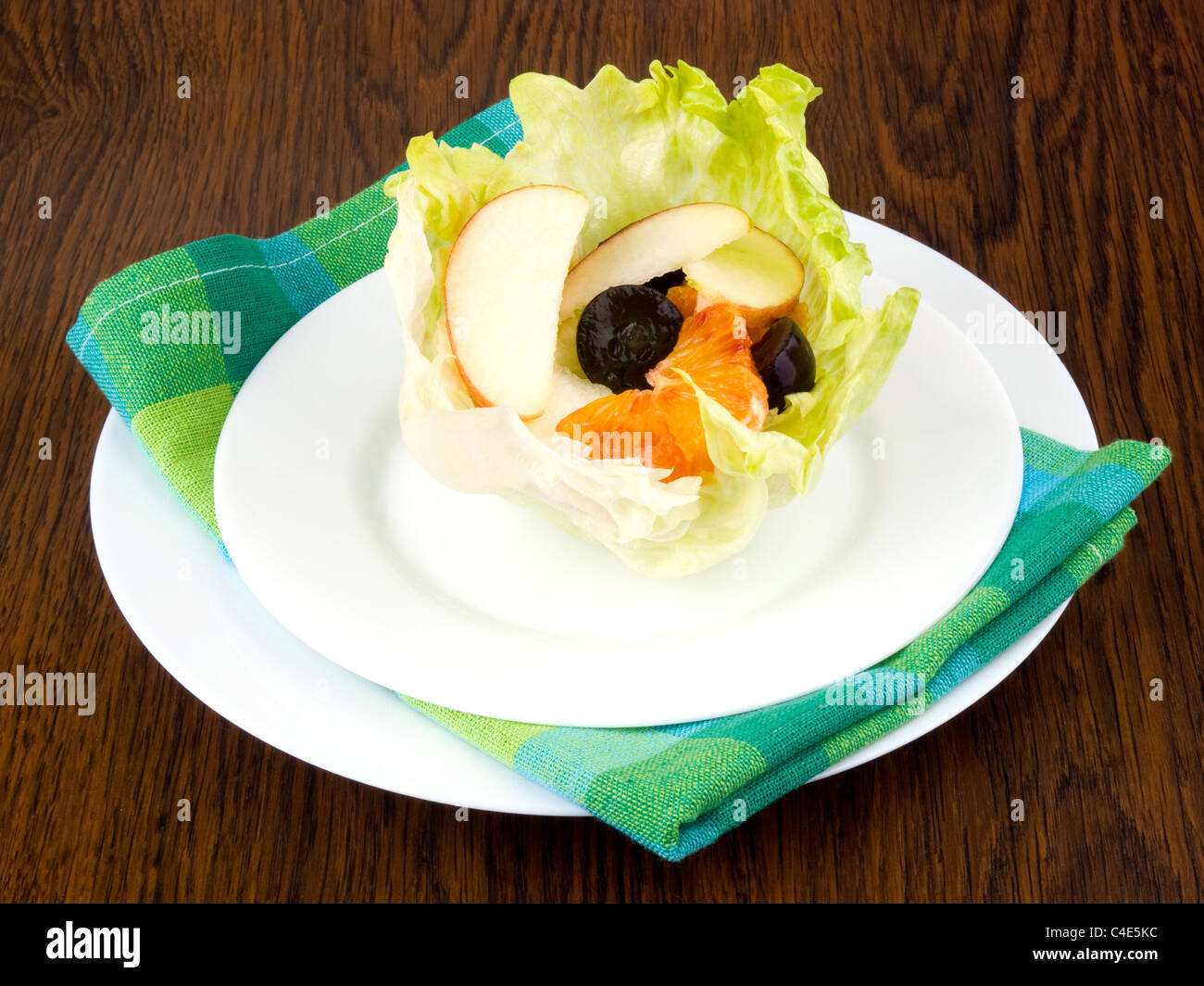 Apfel, Orange und Trauben in Eisbergsalat Blatt auf weißen Teller - Frucht-Salat geschnitten Stockfoto