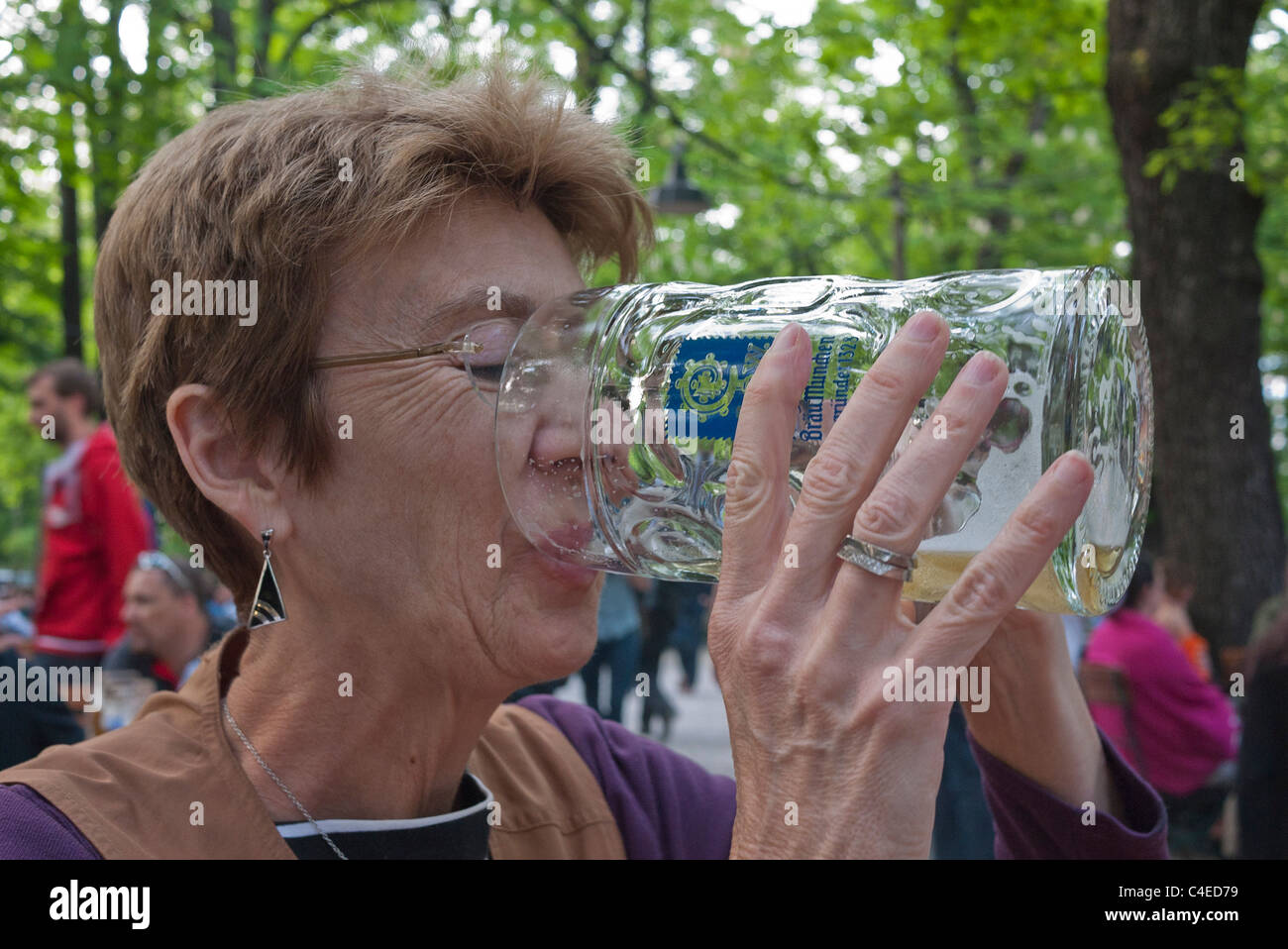 Ein weiblicher Touristen trinkt aus einer sehr großen Bierkrug im Biergarten Augustiner-Keller in München. Stockfoto