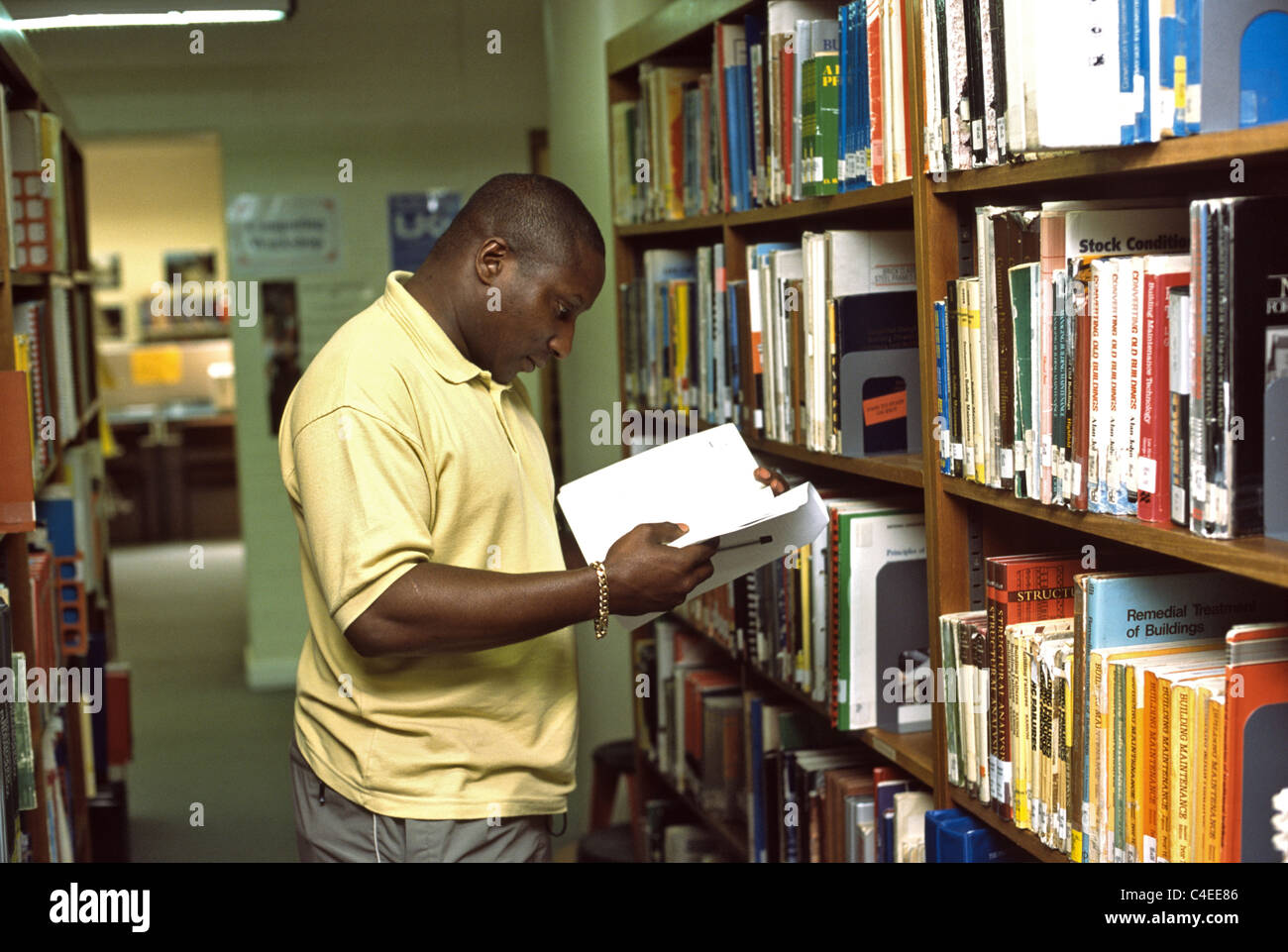 Young Black Man Bücher in der Universitätsbibliothek anschauen Stockfoto