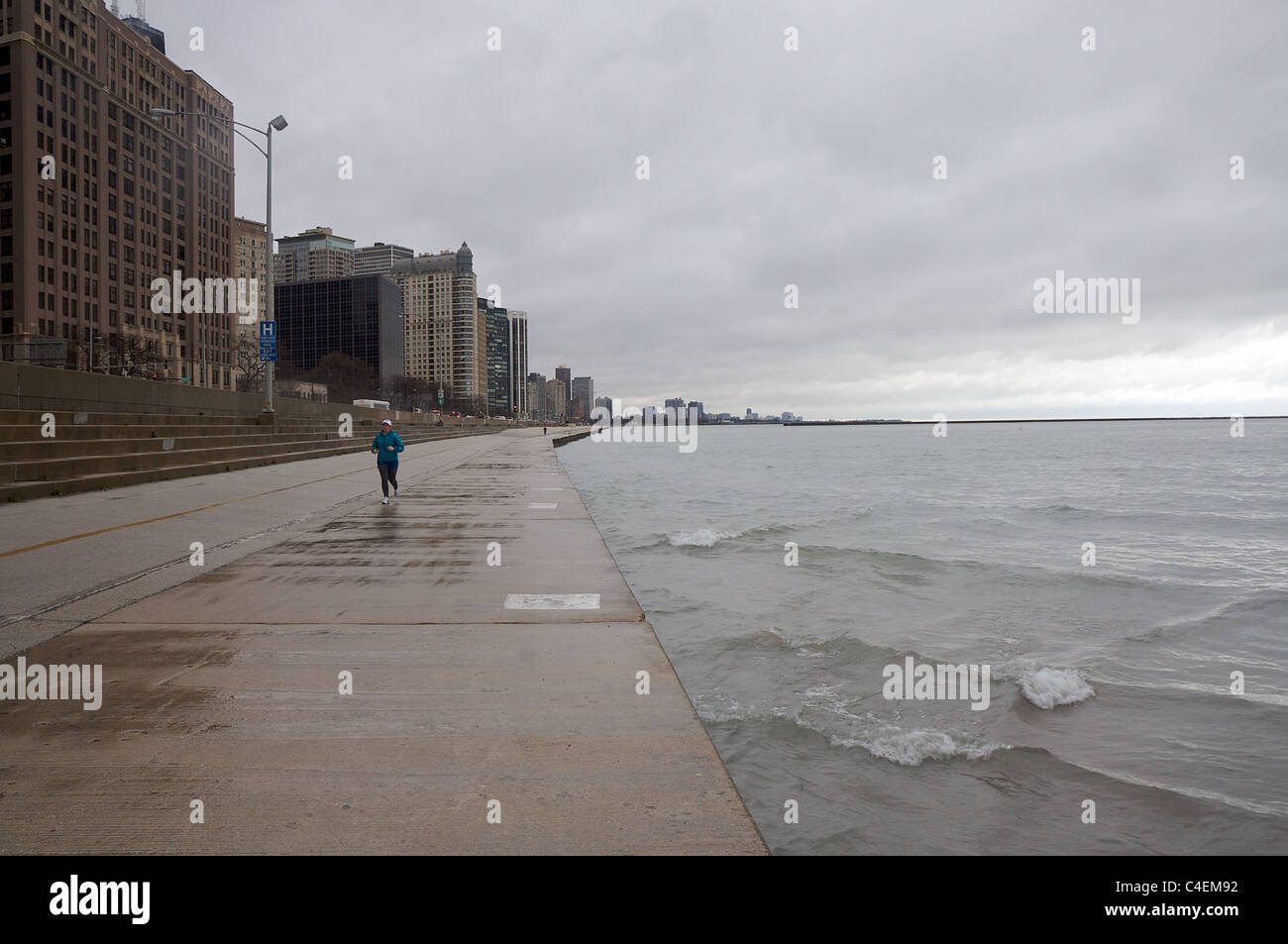 An einem regnerischen Tag in Chicago joggt eine Frau neben Lake Michigan Stockfoto