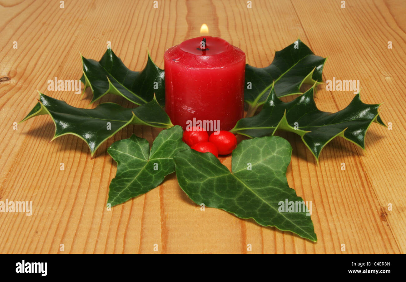 Brennende rote Kerze mit Holly und ivy Stockfoto