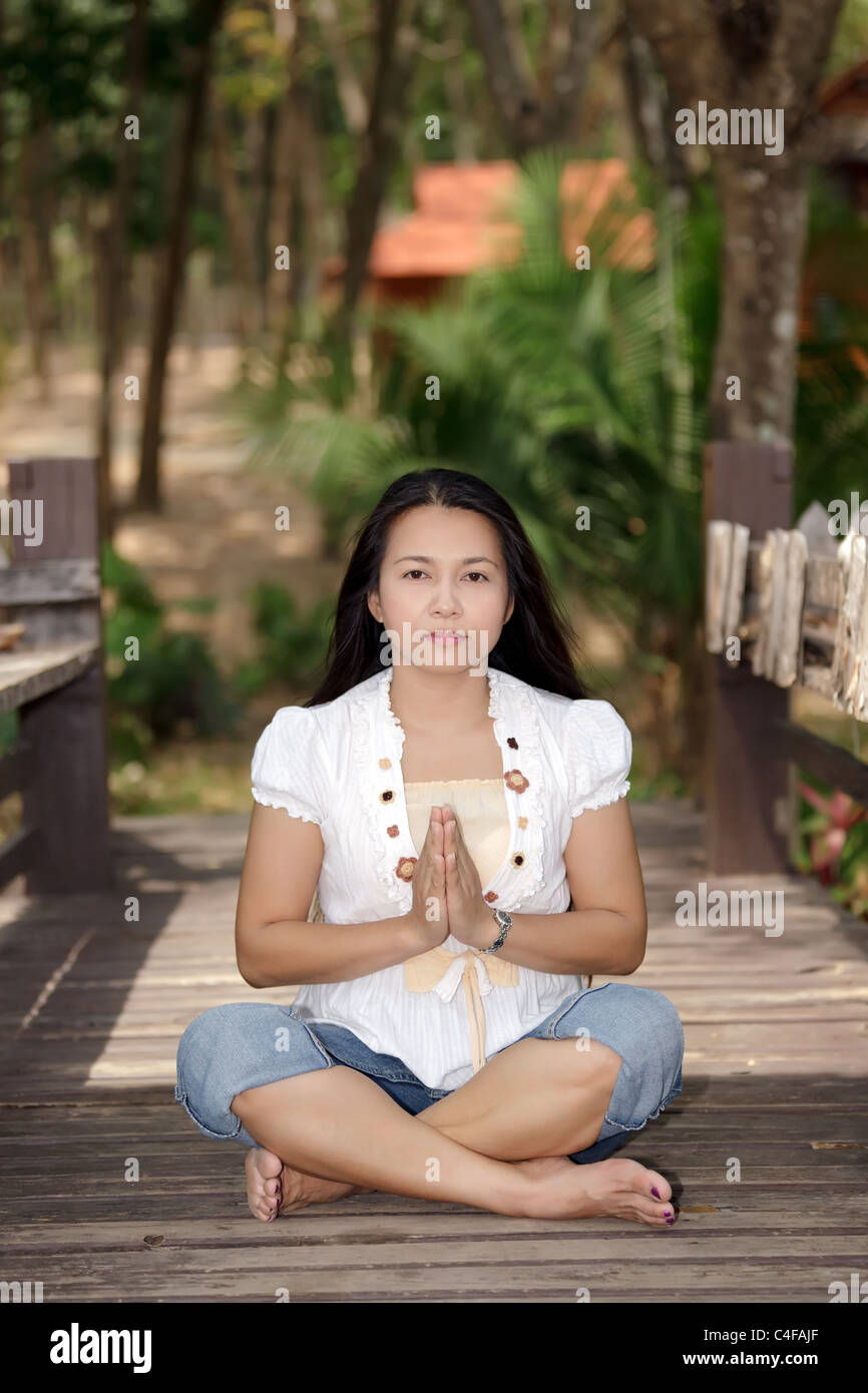 asiatische Frau Meditation über hölzerne Brücke im park Stockfoto