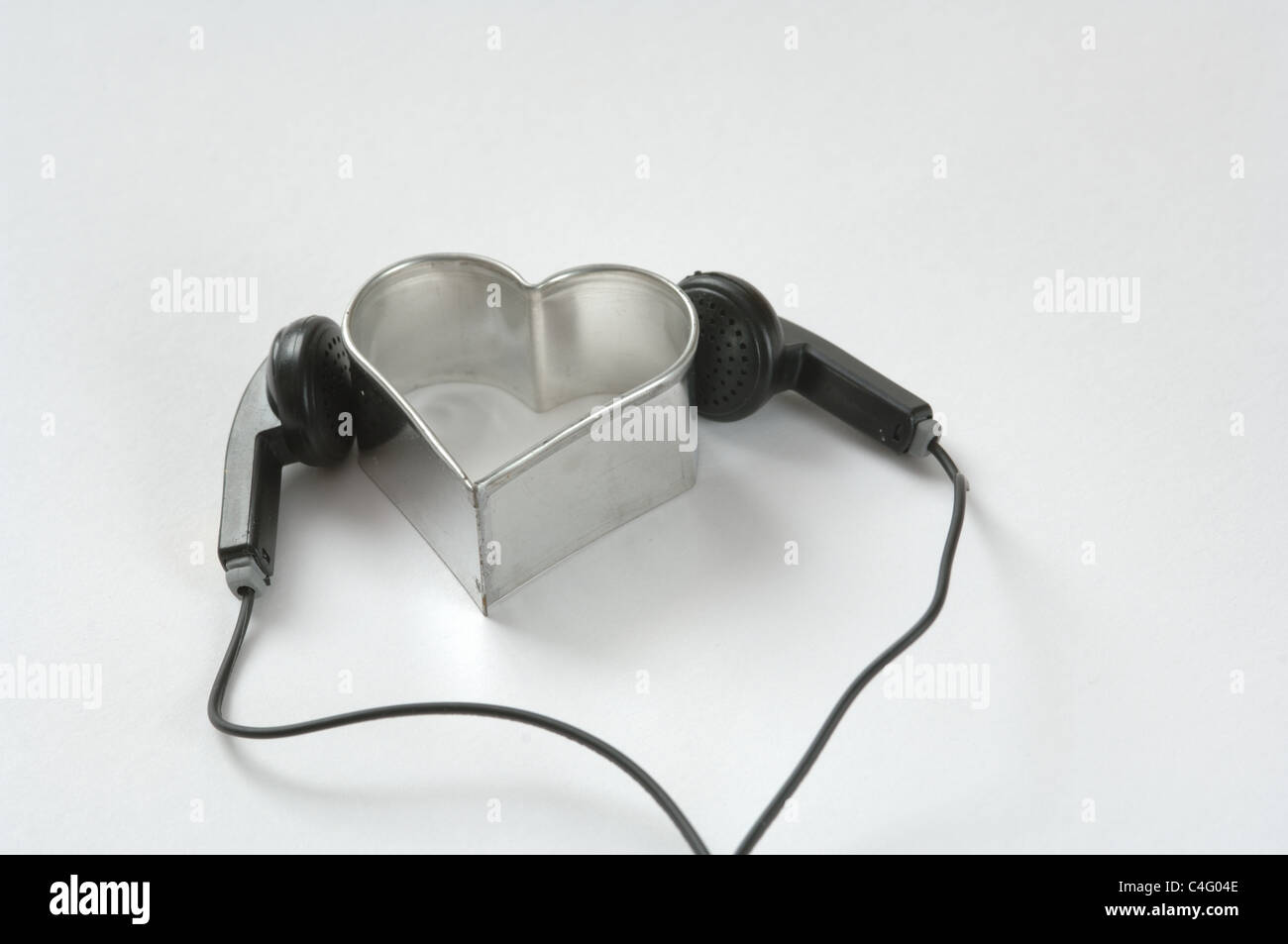 Ohrhörer Und Ein Herzförmiges Ausstecherförmchen. Stockfoto
