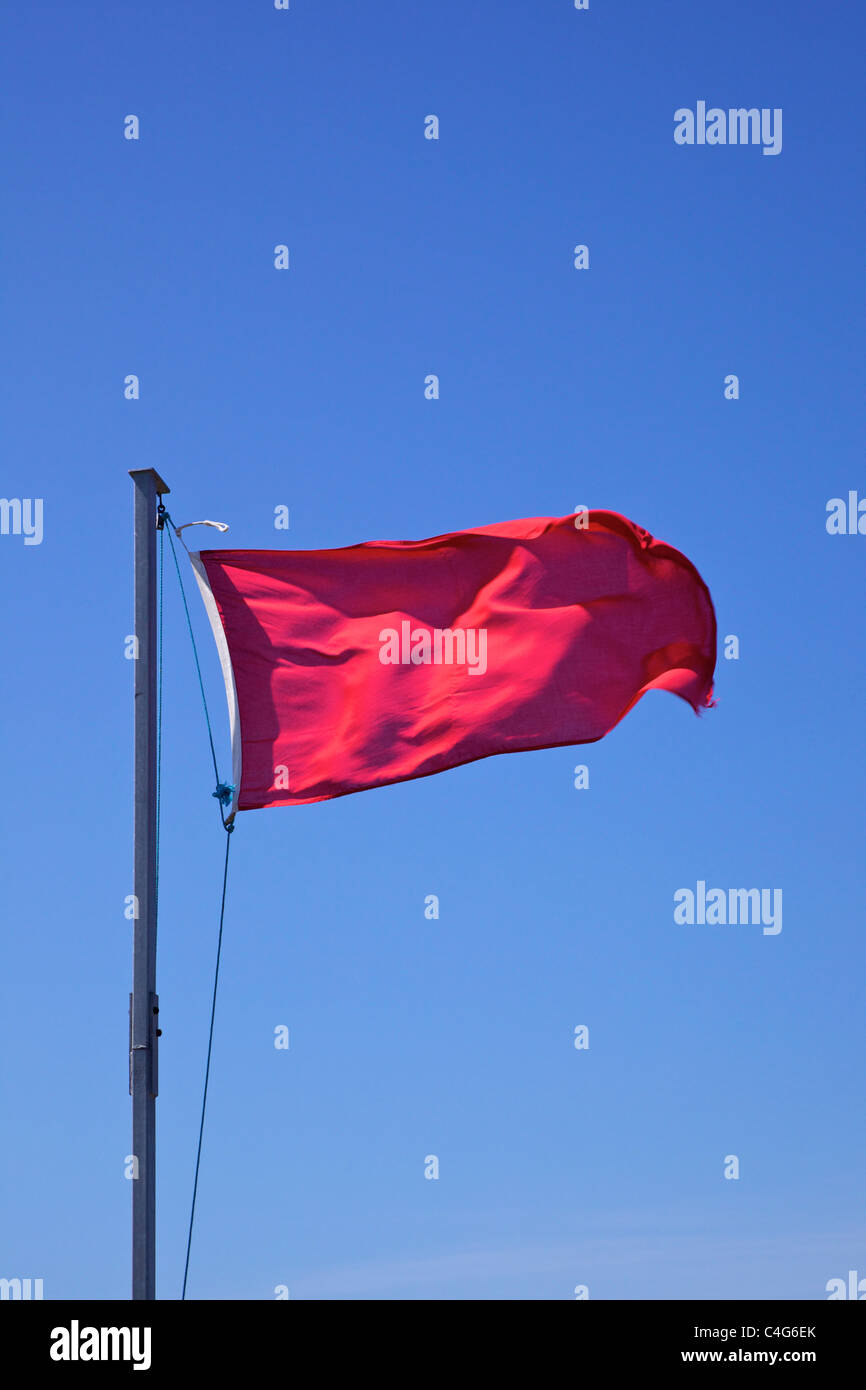Rote Flagge winken gegen blauen Himmel Stockfoto