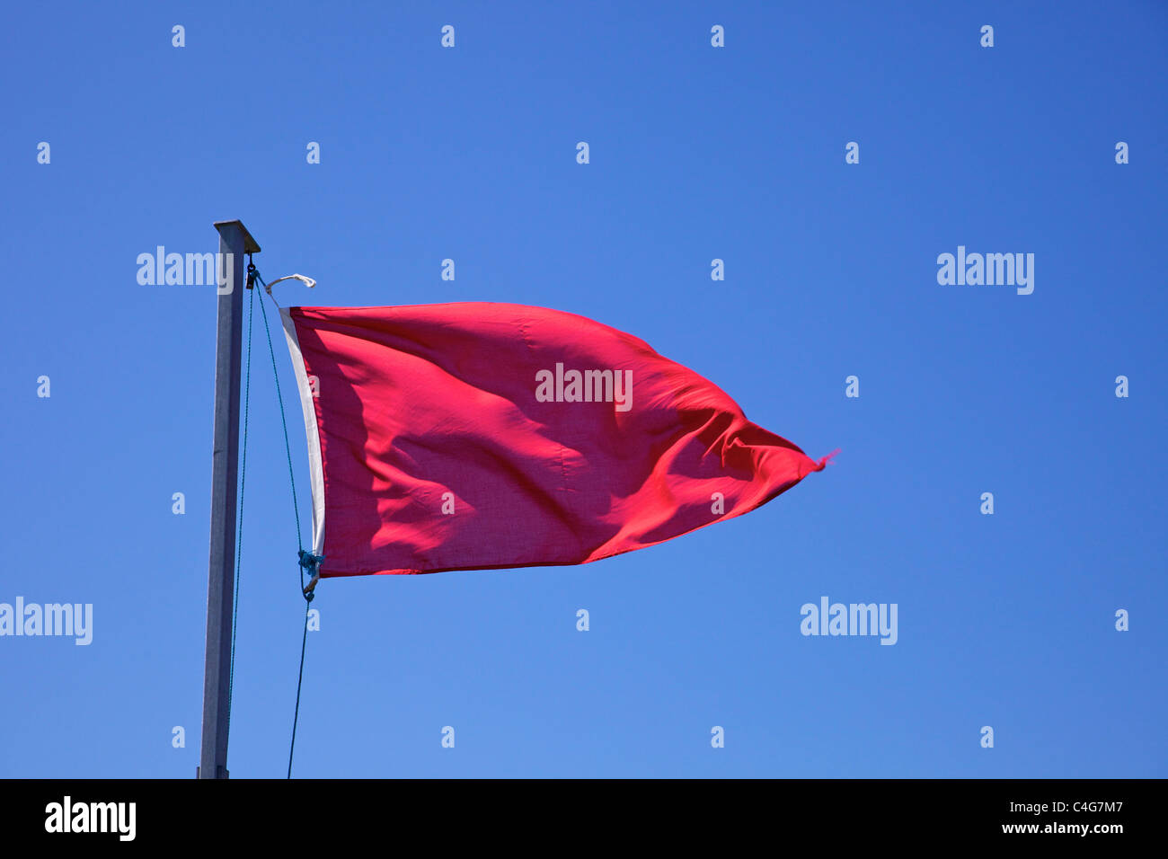 Rote Flagge winken gegen blauen Himmel Stockfoto