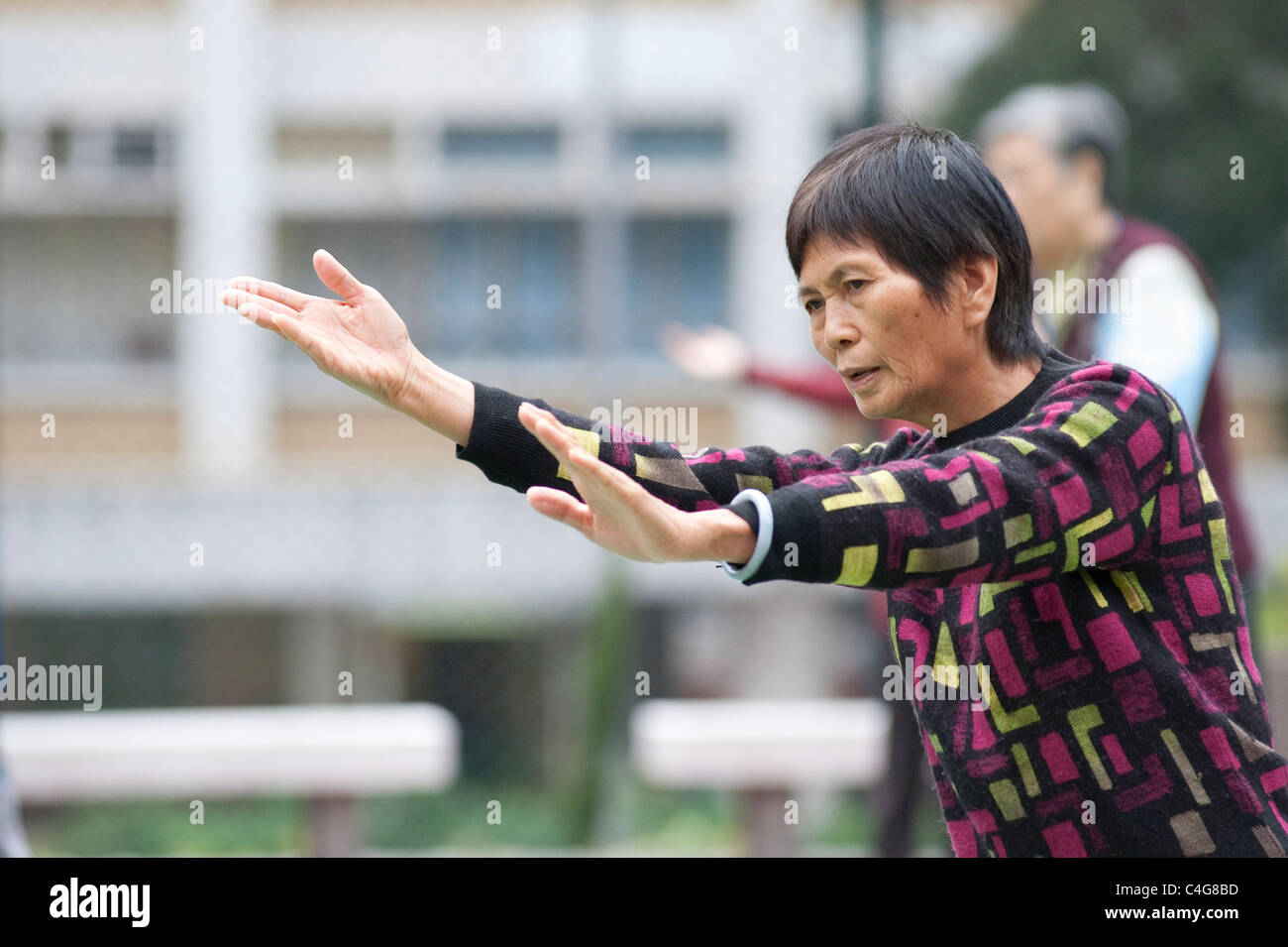 Eine ältere chinesische Dame während eines frühen Morgens Tai Chi Sitzung in Mongkok auf der Halbinsel Kowloon, Hong Kong Stockfoto
