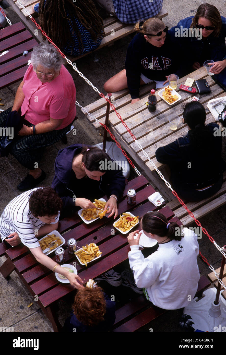 Brighton, Sussex, England. Beliebter Badeort an der südlichen Küste England. Familie isst Fisch und Chips am Meer. Stockfoto
