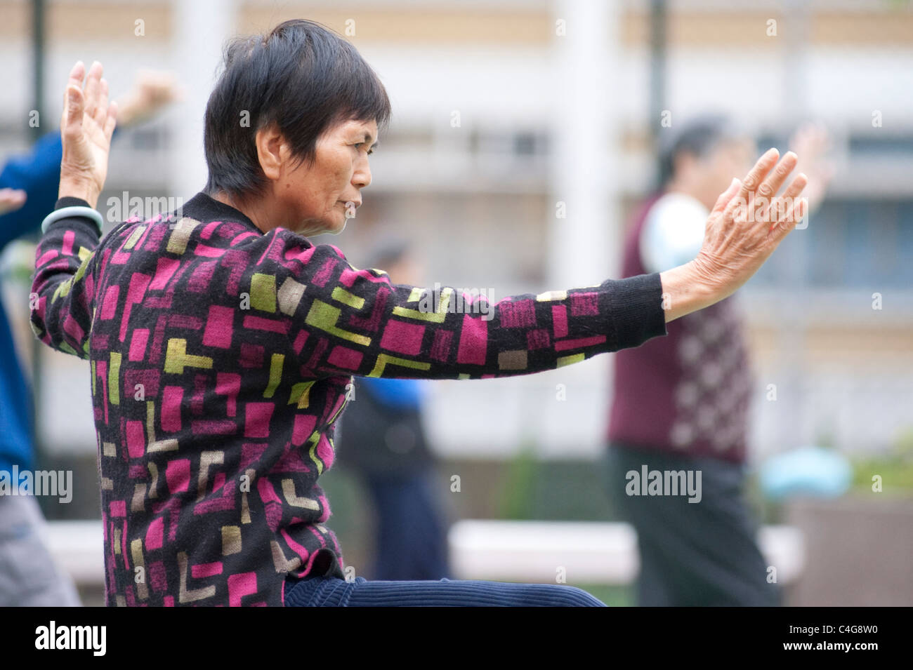 Eine ältere chinesische Dame während eines frühen Morgens Tai Chi Sitzung in Mongkok auf der Halbinsel Kowloon, Hong Kong Stockfoto