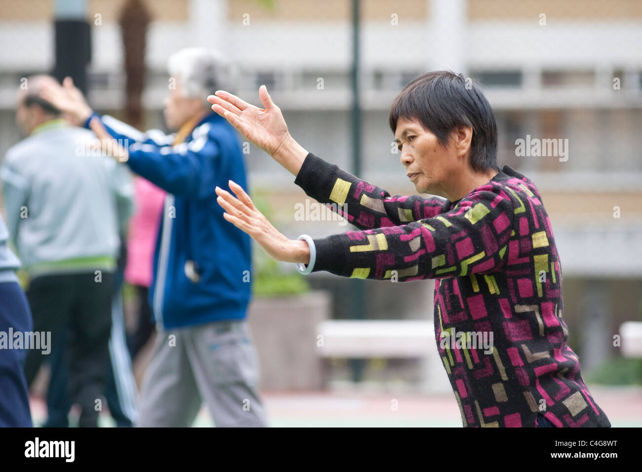 Eine ältere chinesische Dame während einer Sitzung am frühen Morgen in kommunalen Tai Chi in Mongkok auf der Halbinsel Kowloon, Hong Kong Stockfoto