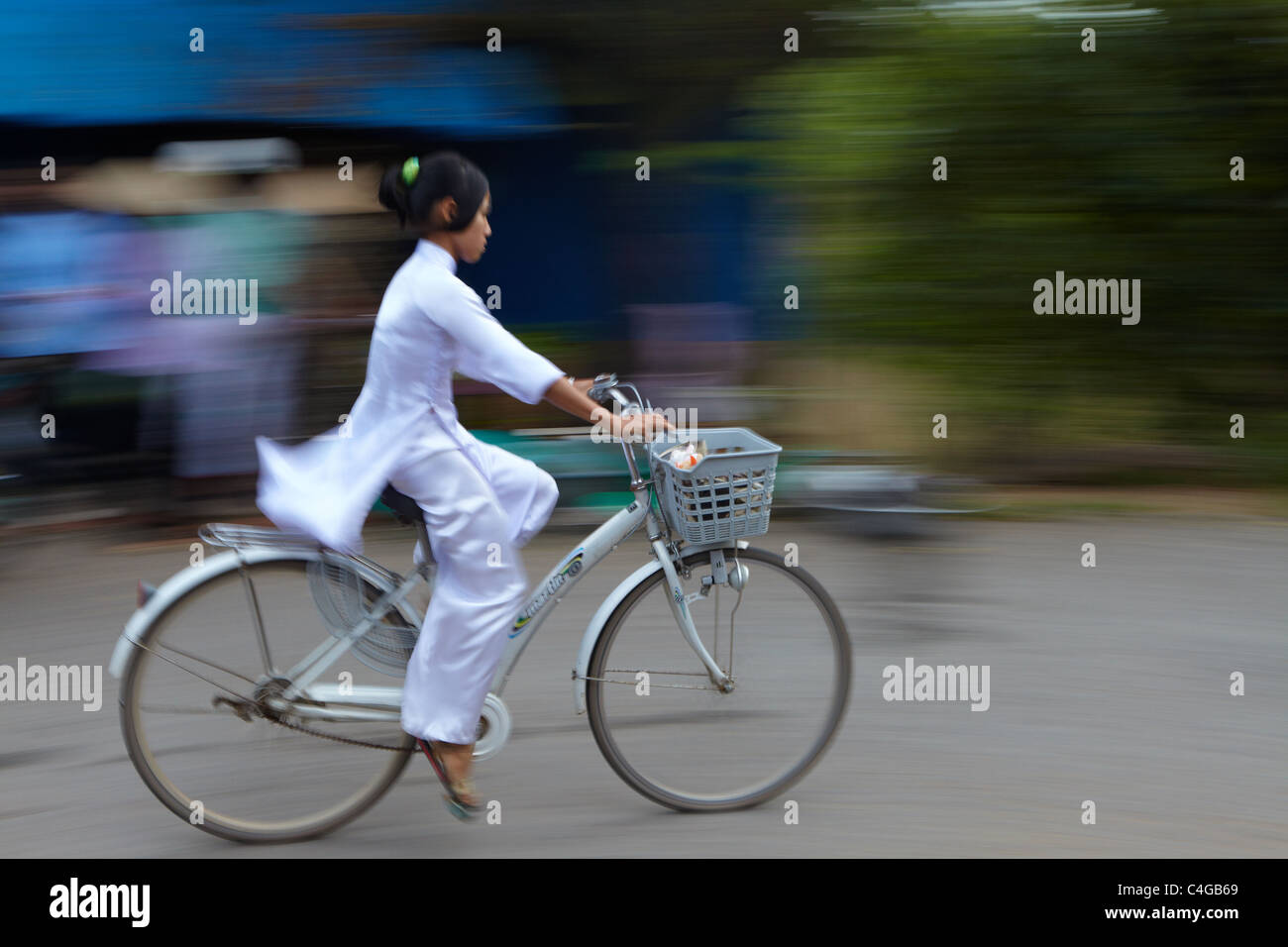 ein Mädchen in Ao Dai auf einem Fahrrad, Mekong-Delta, Vietnam Stockfoto