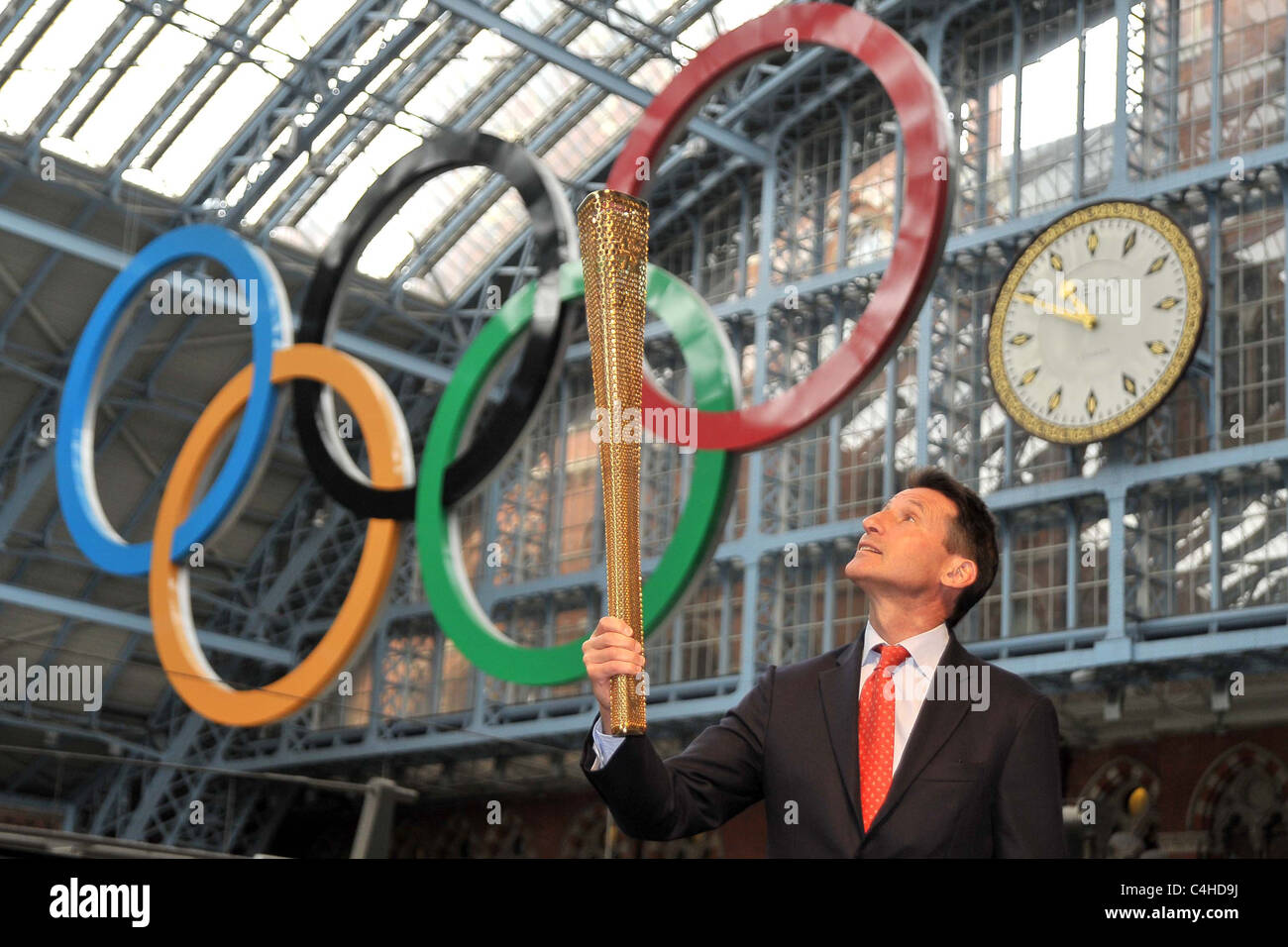 Sebastian Coe (Vorsitzender des LOCOG) schaut an der Fackel, da er es unter den Olympischen Ringen hält. 2012 Olympische Fackel London Stockfoto