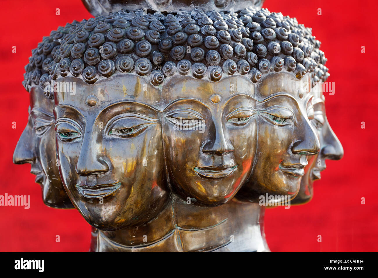 Multi leitete metallischen Buddha-Kopf auf rotem Grund, thailand Stockfoto