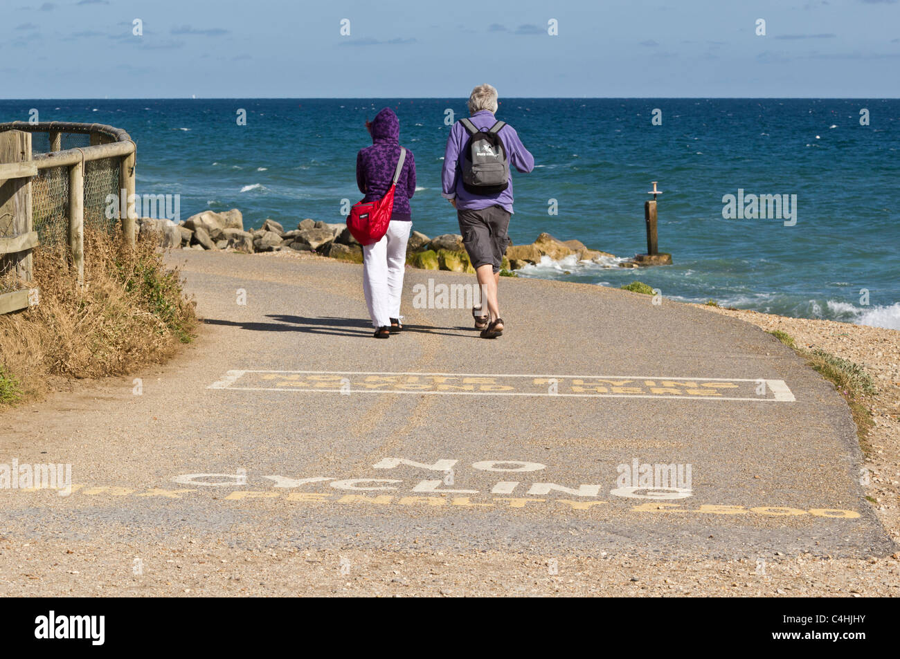 Wanderer auf Küstenweg mit "No Radfahren" und "No Kite Flying" Zeichen auf Pfad im Vordergrund gemalt Stockfoto