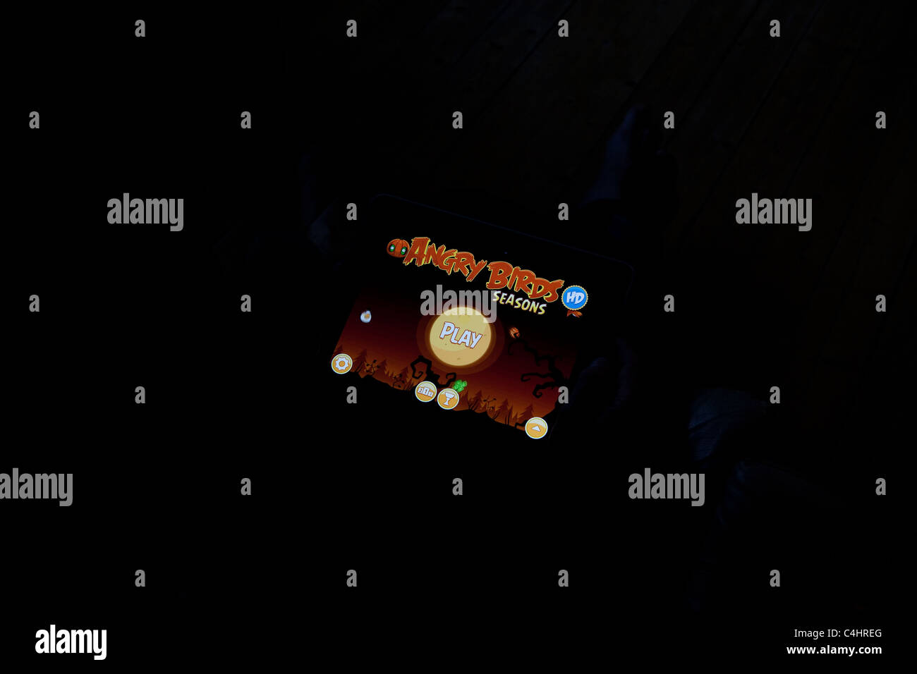 Mann sitzt in der dunklen spielen angry Birds auf seinem Ipad Stockfoto