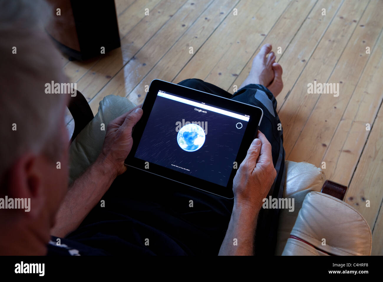 Mann, sitzen und beobachten GoogleEarth auf seinem Ipad Stockfoto