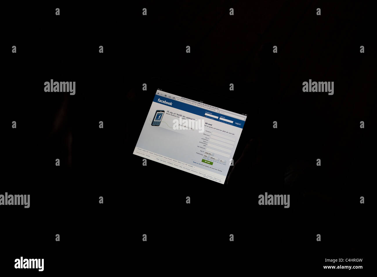 Mann sitzt in der dunklen beobachten Facebook auf seinem Ipad Stockfoto