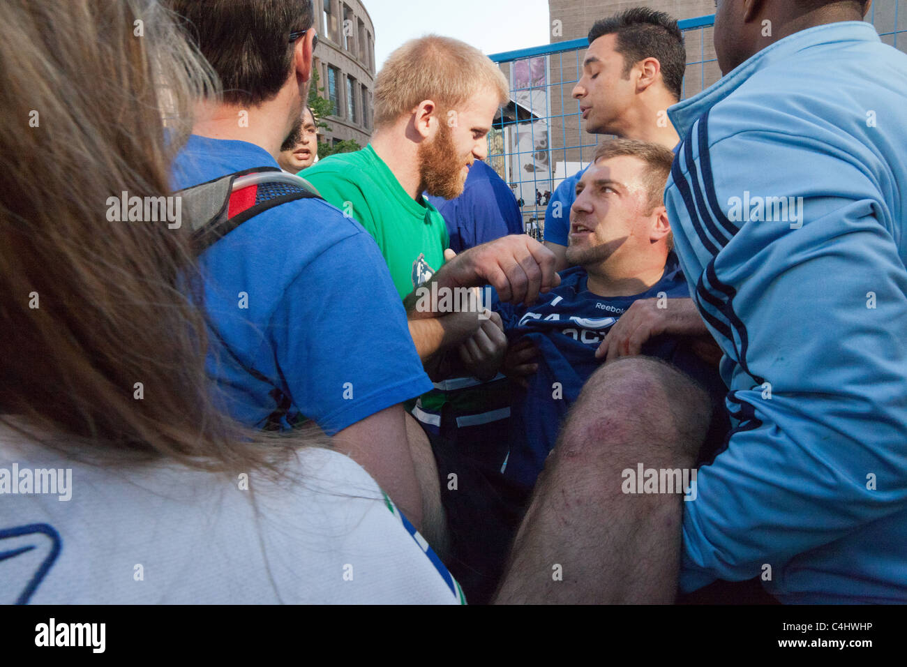 300 Pfund Mann bekommt von der Masse mit einem verdrehten Knöchel befreit, in Spiel 7 des Stanley Cups in der Innenstadt von Vancouver. Stockfoto