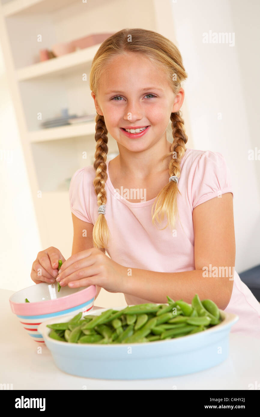 Glückliches Mädchen teilen Erbsen in Küche Stockfoto
