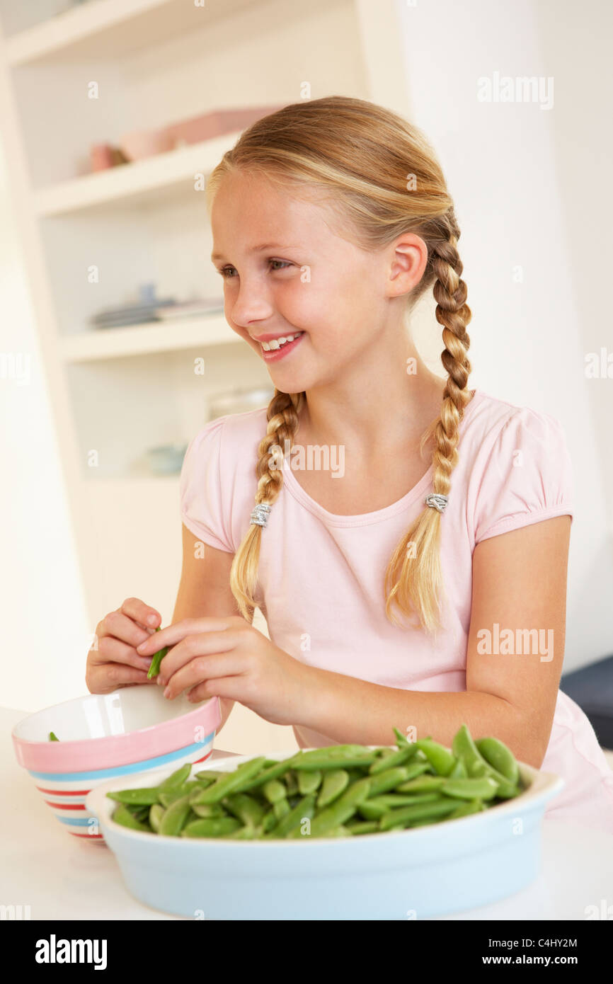 Glückliches Mädchen teilen Erbsen in Küche Stockfoto