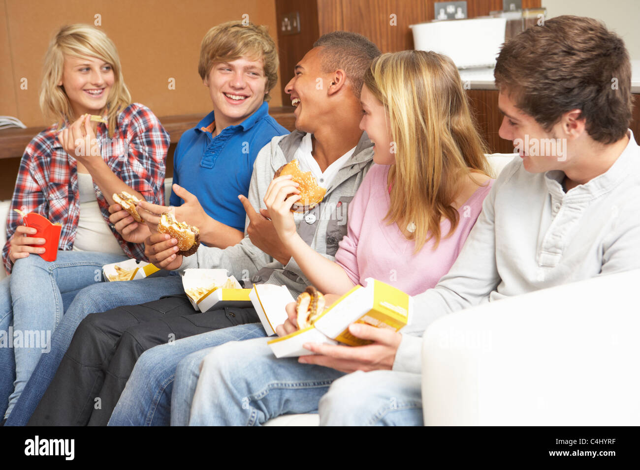 Gruppe von Jugendlichen Freunde sitzen auf dem Sofa zu Hause essen schnell Foo Stockfoto