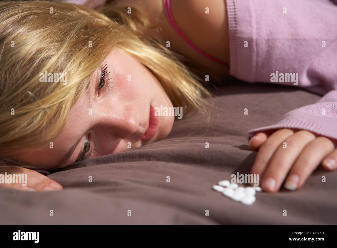 Depressive Teenager-Mädchen sitzen im Schlafzimmer mit Pillen Stockfoto