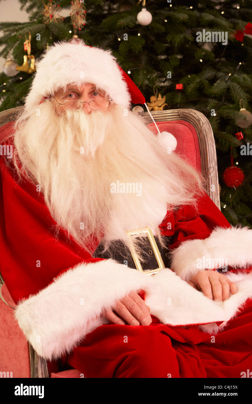 Weihnachtsmann sitzt im Sessel vor Weihnachtsbaum Stockfoto