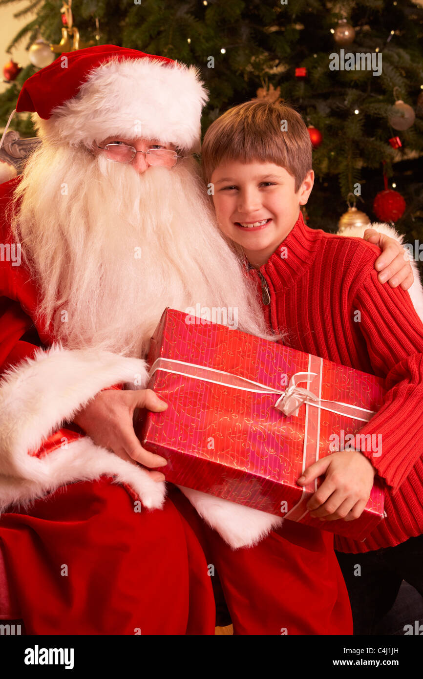 Santa Claus Geschenk an junge vor Weihnachtsbaum Stockfoto