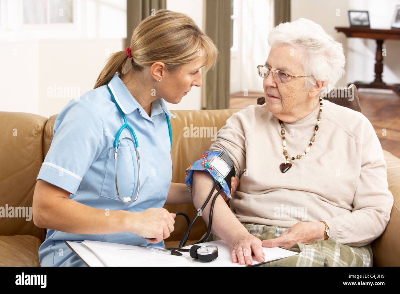 Senior Woman Blutdruck genommen von Gesundheit Besucher zu Hause Stockfoto