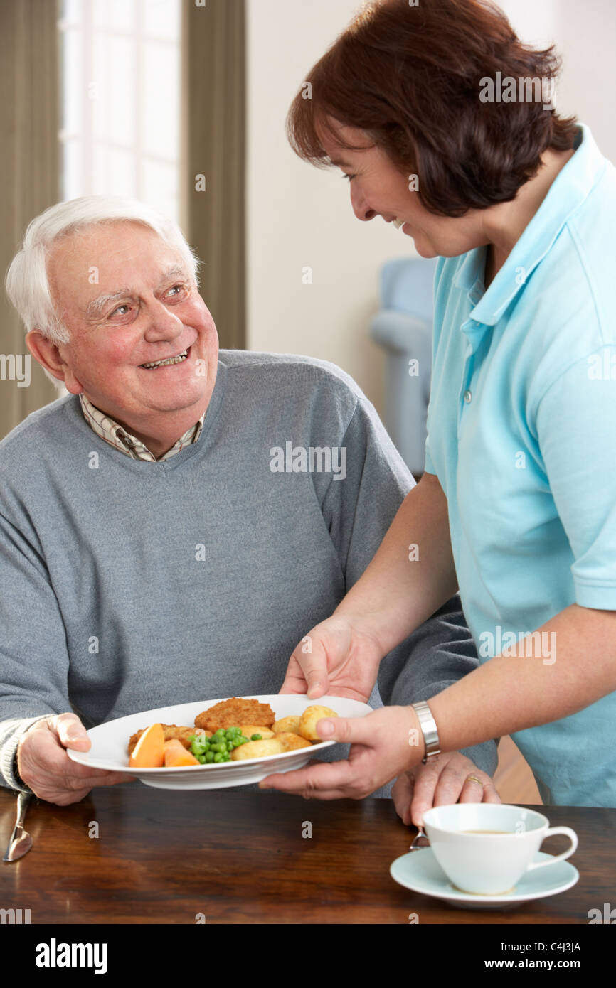Senior woman Mahlzeit serviert wird, durch Betreuer Stockfoto