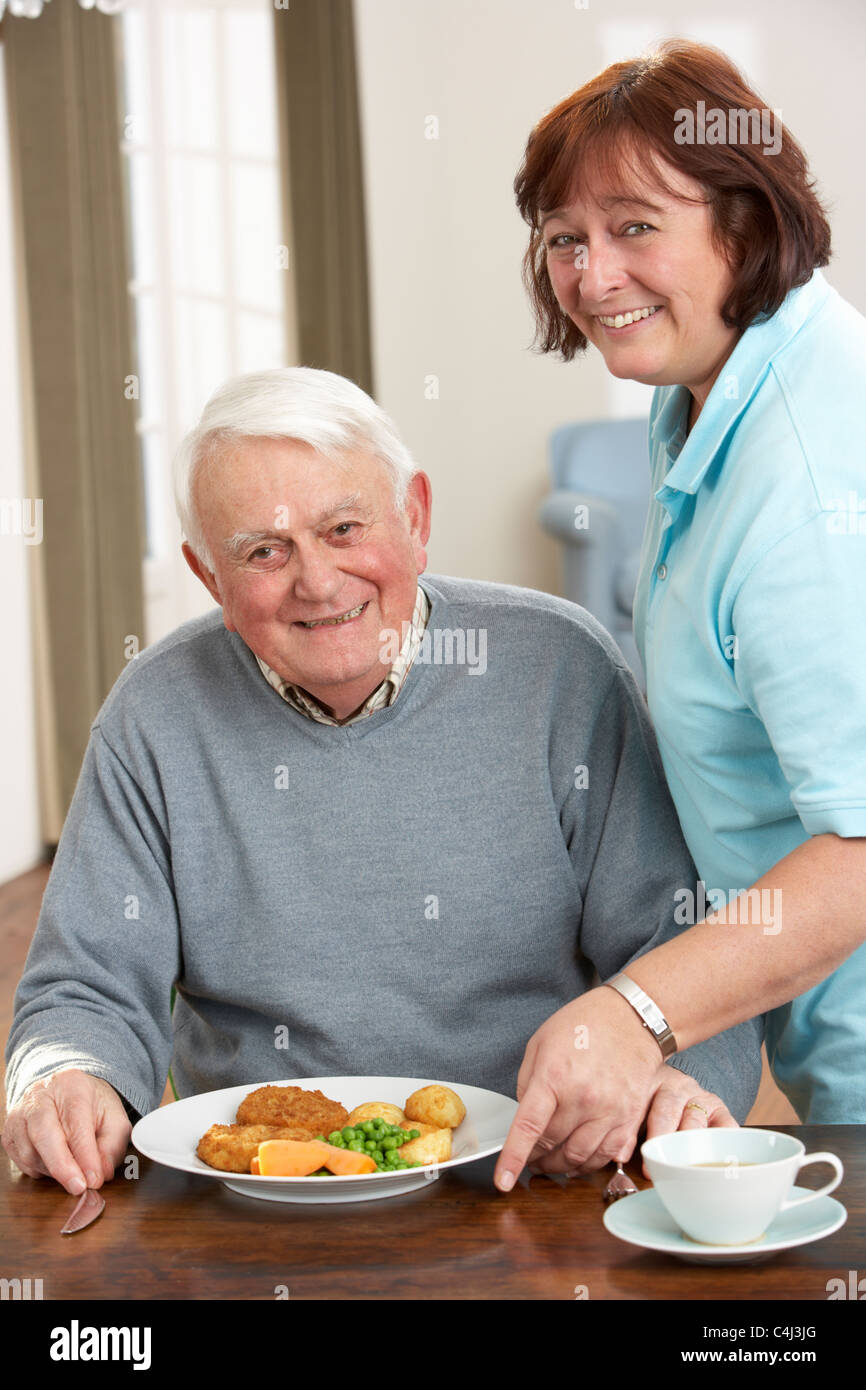 Senior woman Mahlzeit serviert wird, durch Betreuer Stockfoto