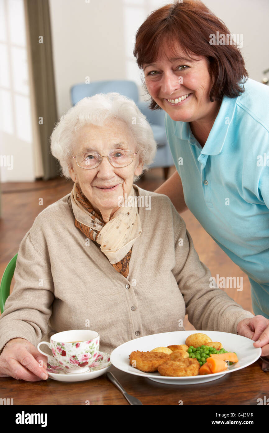 Ältere Frau Mahlzeit serviert wird, durch Betreuer Stockfoto