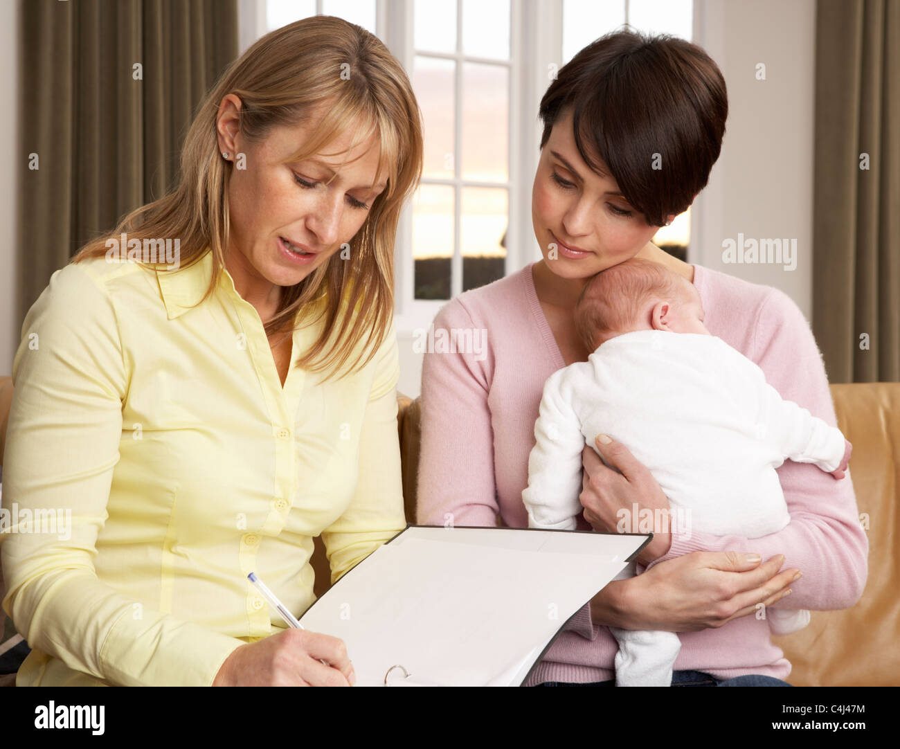 Mutter mit Neugeborenen im Gespräch mit Gesundheit Besucher zu Hause Stockfoto