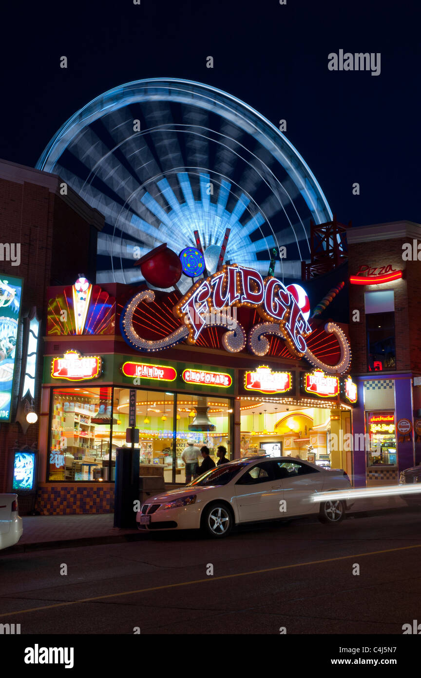 Die helle, bunte Lichter der Clifton Hill in der Nacht mit beweglichem Riesenrad im Hintergrund. Stockfoto