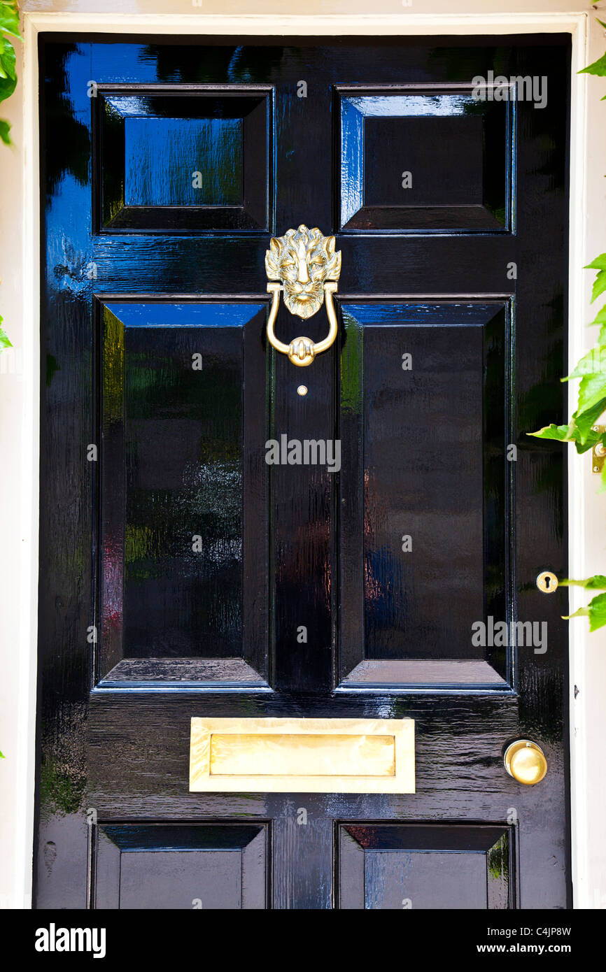 Einen glänzenden Hochglanz schwarz lackiert Haustür mit hochglanzpoliertem Messing Tür Möbel. Stockfoto