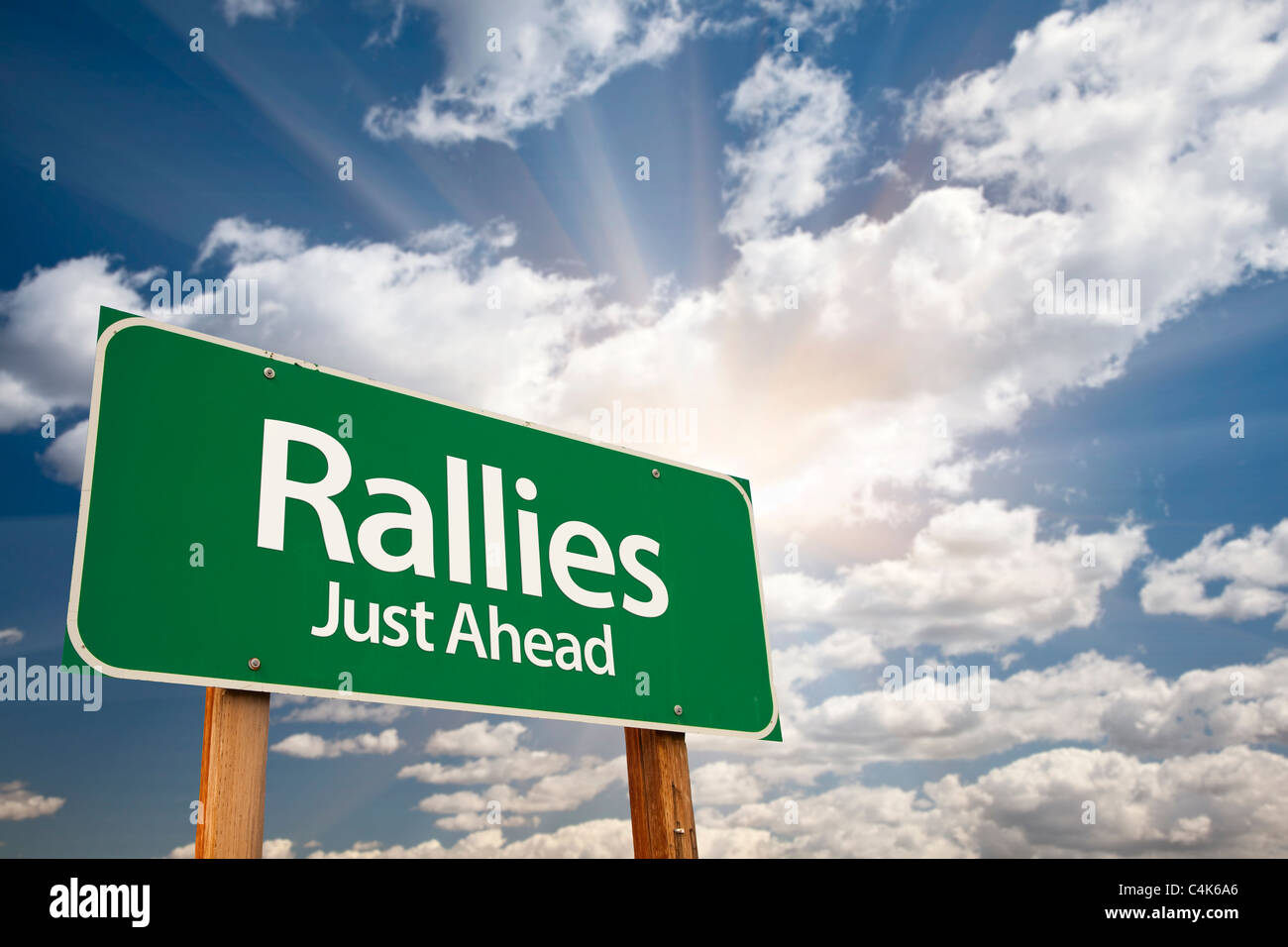 Grüne Verkehrszeichen gegen Wolken und Sunburst Rallyes. Stockfoto