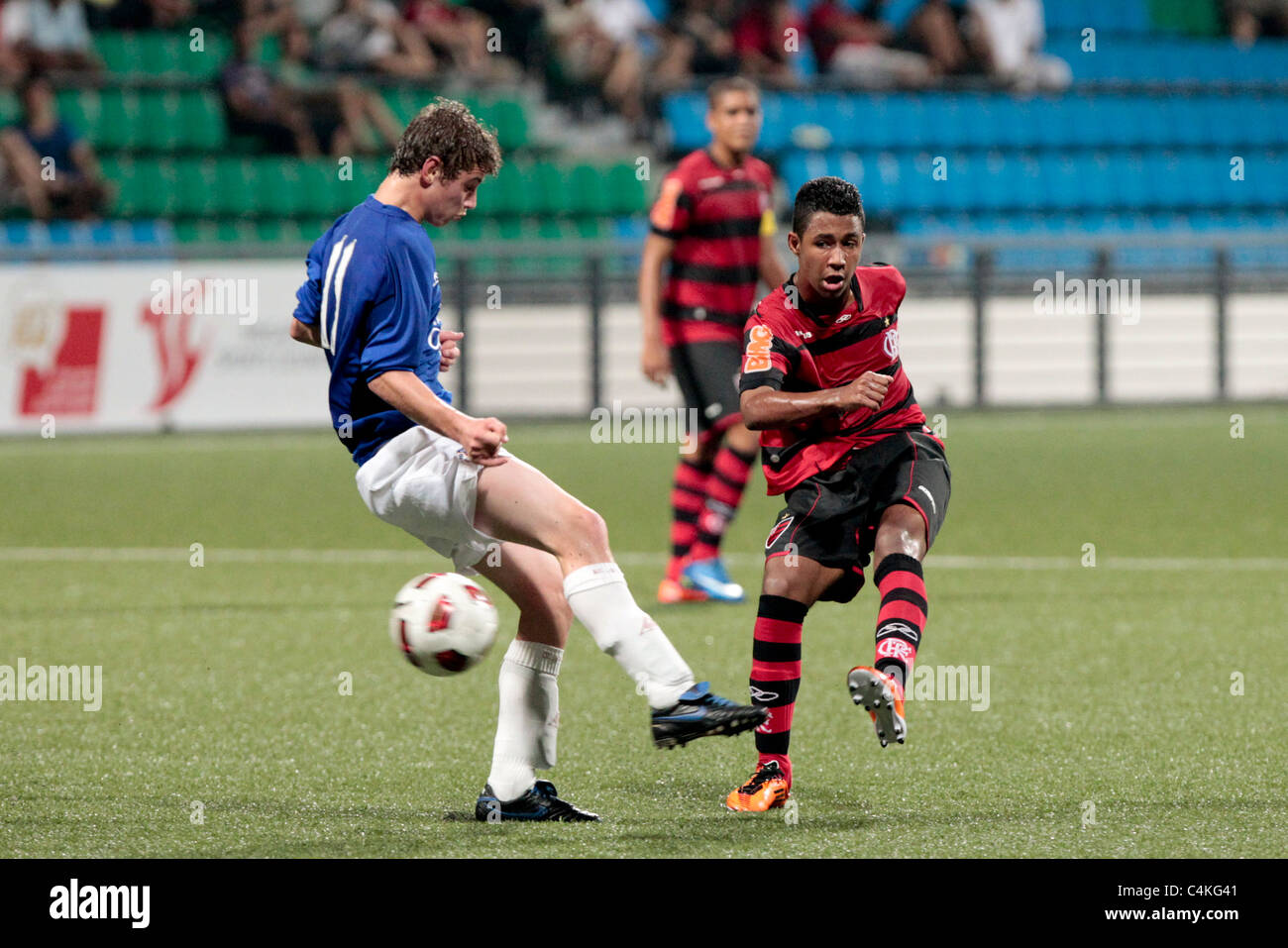 Während die 23. Canon Lion City Cup schießt Ian Evans von CR Flamengo(red) außerhalb der Reichweite von Ryan Ledson. Stockfoto